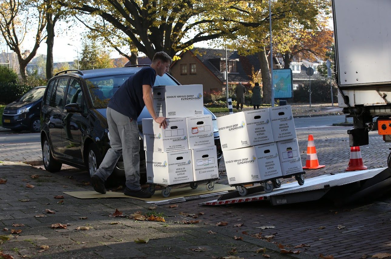SVG-verhuizer laadt verhuisdozen op een steekwagen bij de verhuiswagen